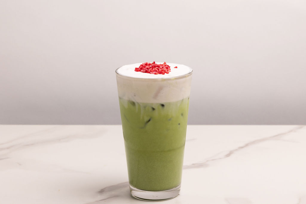 An iced matcha latte with cream foam and strawberry