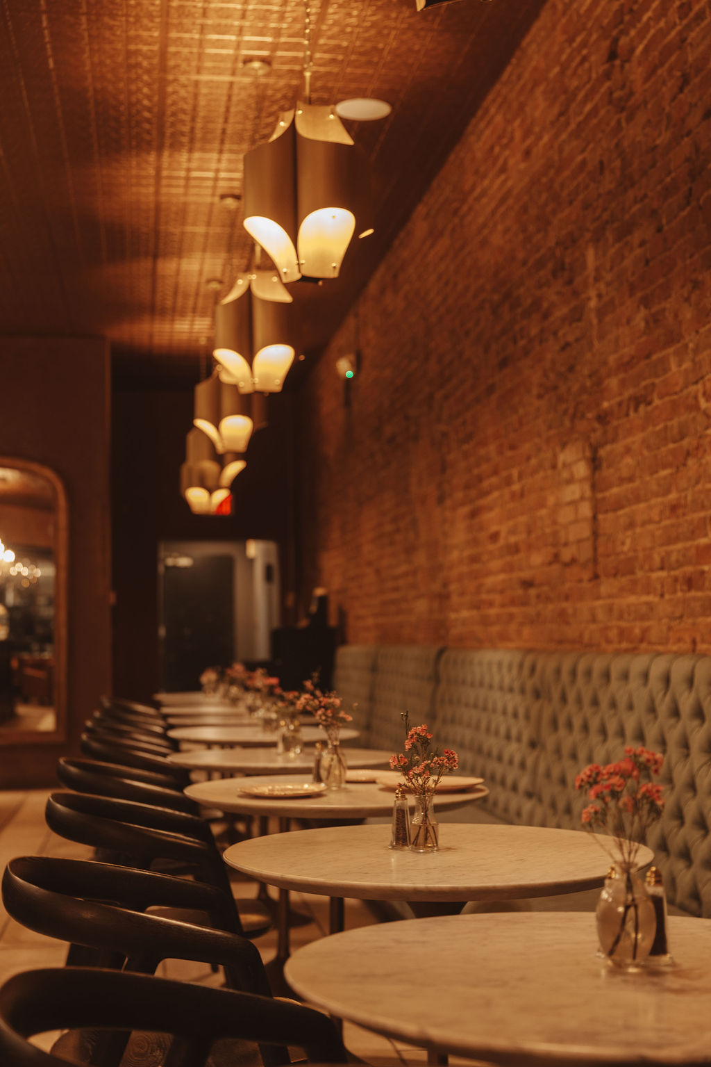 The warm dining room at Sage with brick walls and marble tables