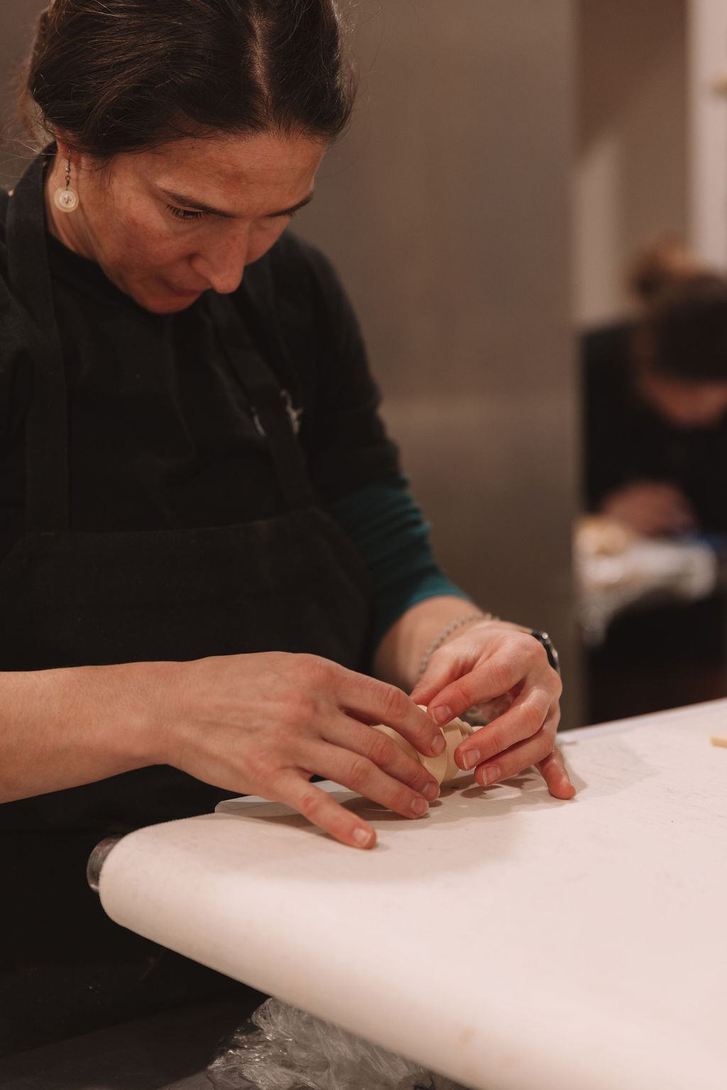 A baker hand-shaping croissant dough on the marble counter